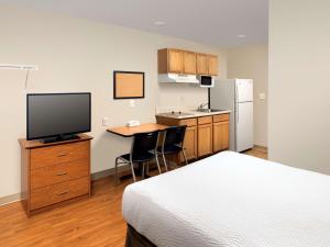 a bedroom with a bed and a desk with a television at WoodSpring Suites Louisville Clarksville in Clarksville
