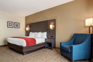 Habitación de hotel con cama y silla azul en Comfort Inn & Suites Millbrook-Prattville, en Millbrook