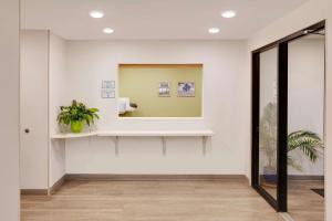 un couloir avec un miroir et une plante en pot dans l'établissement WoodSpring Suites Bakersfield East, à Bakersfield