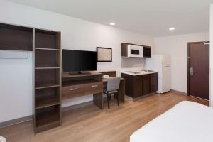 a bedroom with a desk with a computer and a sink at WoodSpring Suites Bakersfield East in Bakersfield