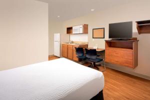 a bedroom with a bed and a desk with a television at WoodSpring Suites Hobbs in Air Base City