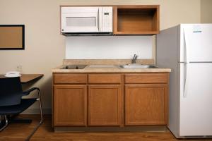 a kitchen with a sink and a white refrigerator at WoodSpring Suites Hobbs in Air Base City