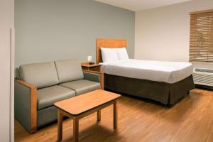 um quarto com uma cama, um sofá e uma cadeira em WoodSpring Suites Hobbs em Air Base City