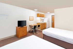 a hotel room with two beds and a desk with a television at WoodSpring Suites Sioux Falls in Sioux Falls
