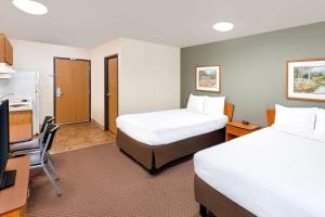 a hotel room with two beds and a television at WoodSpring Suites Sioux Falls in Sioux Falls
