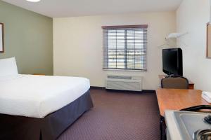a bedroom with a bed and a desk and a television at WoodSpring Suites Fort Wayne in Fort Wayne