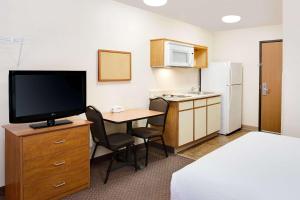 een hotelkamer met een bureau, een televisie en een keuken bij WoodSpring Suites Fort Wayne in Fort Wayne