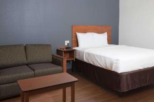 a hotel room with a bed and a couch at WoodSpring Suites Lafayette in Lafayette
