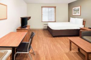 a hotel room with a bed and a desk and a table at WoodSpring Suites Columbus NE I-270 Airport in Gahanna