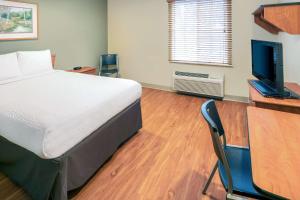 a bedroom with a bed and a desk with a computer at WoodSpring Suites Columbus NE I-270 Airport in Gahanna