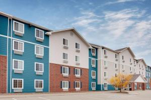 una fila de edificios de apartamentos en un estacionamiento en WoodSpring Suites Ankeny Des Moines, en Ankeny