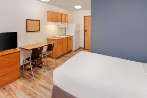 Zimmer mit einem Bett, einem Schreibtisch und einer Küche in der Unterkunft WoodSpring Suites Ankeny Des Moines in Ankeny