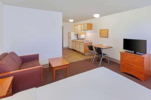 ein Wohnzimmer mit einem Sofa und einem TV sowie eine Küche in der Unterkunft WoodSpring Suites Ankeny Des Moines in Ankeny