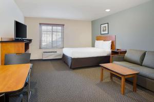 a hotel room with a bed and a couch at WoodSpring Suites Columbus North I-270 in Columbus