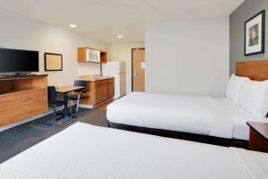 a hotel room with two beds and a flat screen tv at WoodSpring Suites Columbus North I-270 in Columbus