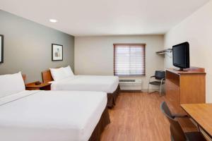 a hotel room with two beds and a flat screen tv at WoodSpring Suites Lake Charles in Lake Charles