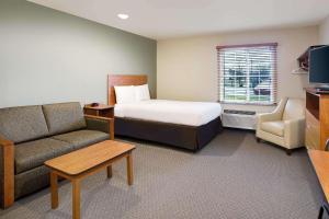 a hotel room with a bed and a couch at WoodSpring Suites Fredericksburg in Fredericksburg