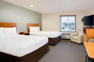 a hotel room with two beds and a television at WoodSpring Suites Fredericksburg in Fredericksburg