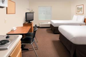 a hotel room with two beds and a desk with a television at WoodSpring Suites Knoxville Airport in Alcoa