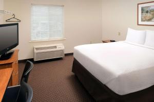 a hotel room with a bed and a flat screen tv at WoodSpring Suites Knoxville Airport in Alcoa