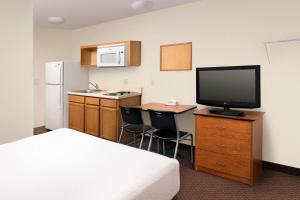 a hotel room with a bed and a desk with a television at WoodSpring Suites Knoxville Airport in Alcoa