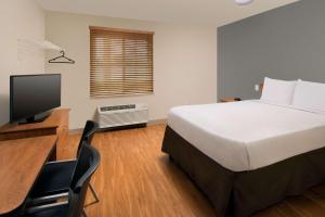 a bedroom with a bed and a desk with a television at WoodSpring Suites Memphis Northeast in Memphis