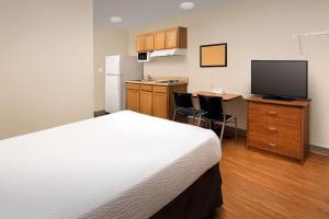 a room with a bed and a kitchen with a television at WoodSpring Suites Memphis East I-40 in Memphis