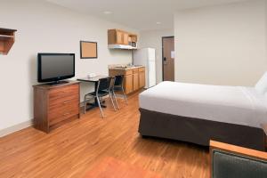 ein Hotelzimmer mit einem Bett und einem Schreibtisch mit einem TV in der Unterkunft WoodSpring Suites Memphis Northeast in Memphis