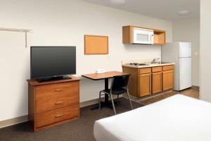 a hotel room with a desk with a television and a kitchen at WoodSpring Suites Spartanburg Duncan in Duncan