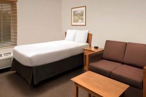 a hotel room with a bed and a couch at WoodSpring Suites Spartanburg Duncan in Duncan