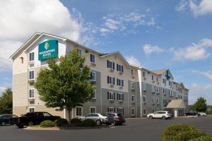 un gran edificio con coches estacionados en un estacionamiento en WoodSpring Suites Greenville Simpsonville en Simpsonville