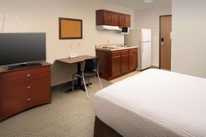 um quarto de hotel com uma cama e uma secretária com uma televisão em WoodSpring Suites Waco near University em Waco