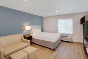 a bedroom with a bed and a couch and a chair at WoodSpring Suites Nashville near Rivergate in Goodlettsville