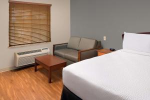 a hotel room with a bed and a chair at WoodSpring Suites Memphis Southeast in Memphis
