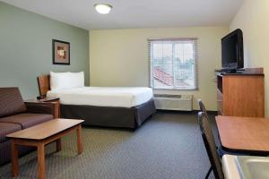 リッチモンドにあるWoodSpring Suites Richmond West I-64のベッド、ソファ、テレビが備わるホテルルームです。