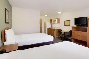 a hotel room with two beds and a television at WoodSpring Suites Richmond West I-64 in Richmond