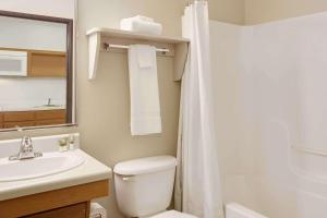 a bathroom with a toilet and a sink and a mirror at WoodSpring Suites Richmond West I-64 in Richmond +12 photos