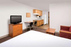 a room with a bed and a television and a kitchen at WoodSpring Suites Austin North I-35 in Austin