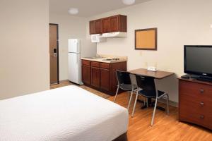 a hotel room with a bed and a kitchen with a table and a television at WoodSpring Suites San Antonio Fort Sam in San Antonio