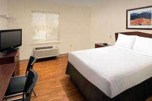 a bedroom with a bed and a desk with a television at WoodSpring Suites San Antonio Fort Sam in San Antonio