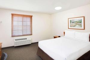 WoodSpring Suites Houston Willowbrook في هيوستن: غرفة نوم بسرير ابيض كبير ونافذة