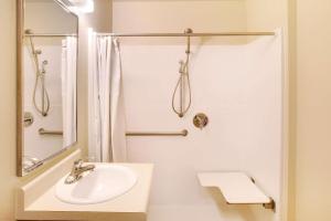 Un baño blanco con lavabo y ducha. en WoodSpring Suites San Antonio South, en San Antonio