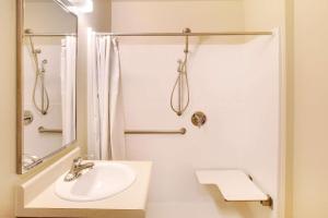 a white bathroom with a sink and a shower at WoodSpring Suites San Antonio South in San Antonio