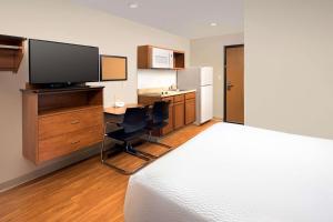 a bedroom with a bed and a desk with a television at WoodSpring Suites San Angelo in San Angelo