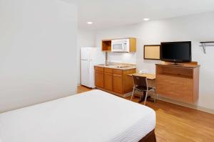 Zimmer mit einem Bett und einer Küche mit einer Mikrowelle in der Unterkunft WoodSpring Suites College Station in College Station