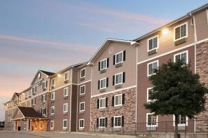un gran edificio de apartamentos con un árbol delante en WoodSpring Suites College Station, en College Station