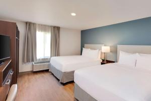 um quarto de hotel com duas camas e uma televisão de ecrã plano em WoodSpring Suites Houston Northwest em Houston