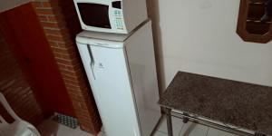 a microwave sitting on top of a refrigerator at Pousada Danza - Centro in Poços de Caldas