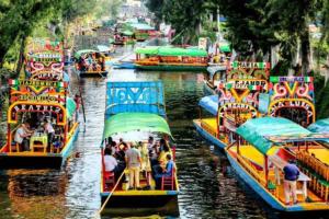 a group of boats in a river with people on them at Xochimilco Hermoso Departamento Loft junto a Trajineras in Mexico City