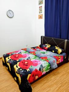 a bed with a colorful blanket on the floor with a clock at Homes Asrafiq - Homestay Merlimau Serkam Melaka in Merlimau